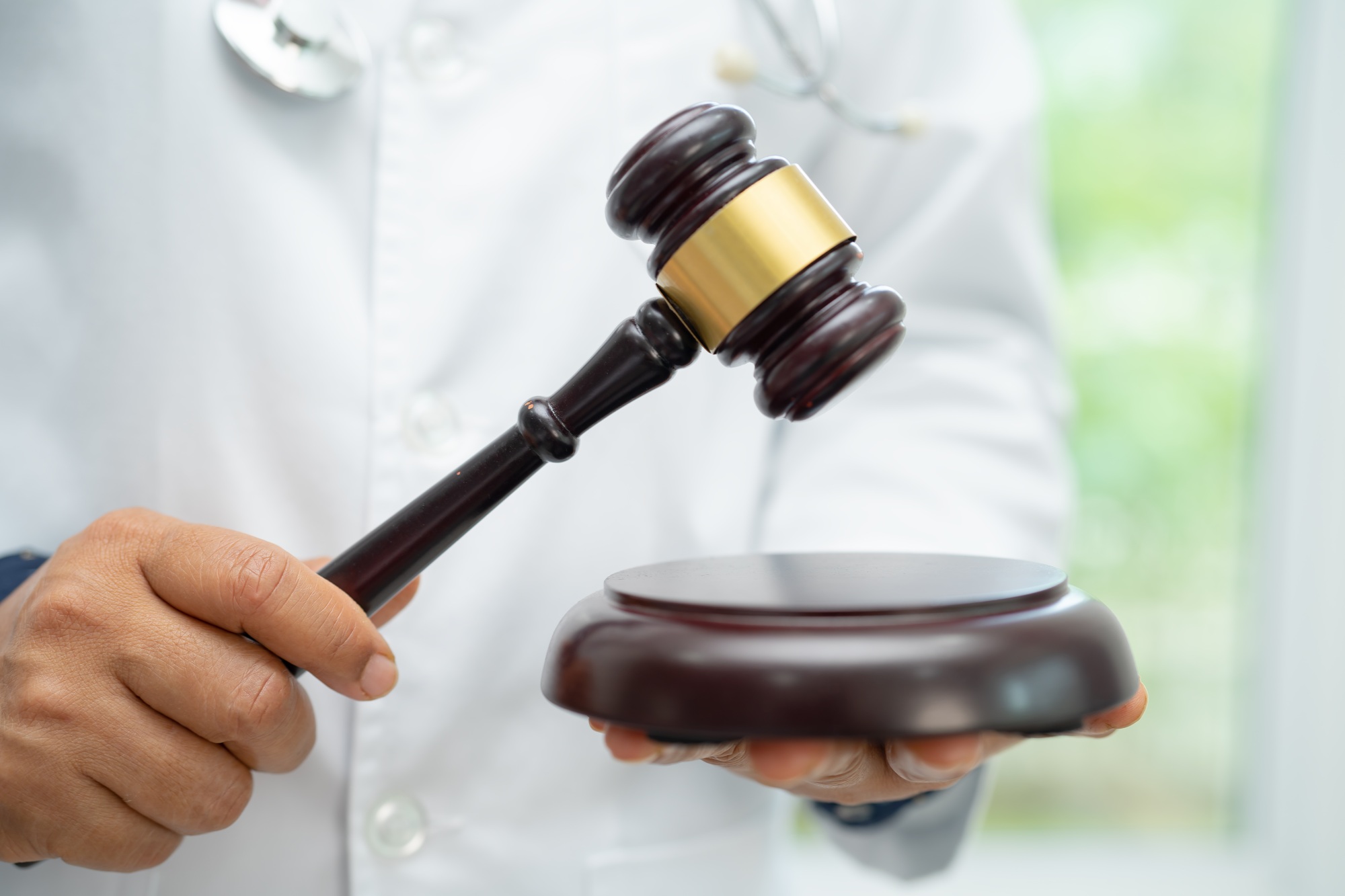 Doctor holding judge gavel, forensic medicine, medical law and crime justice concept.